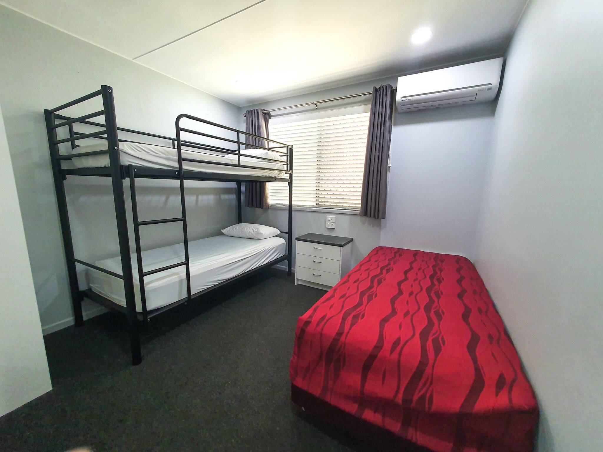 A bunk bed room with a single bed and a desk.