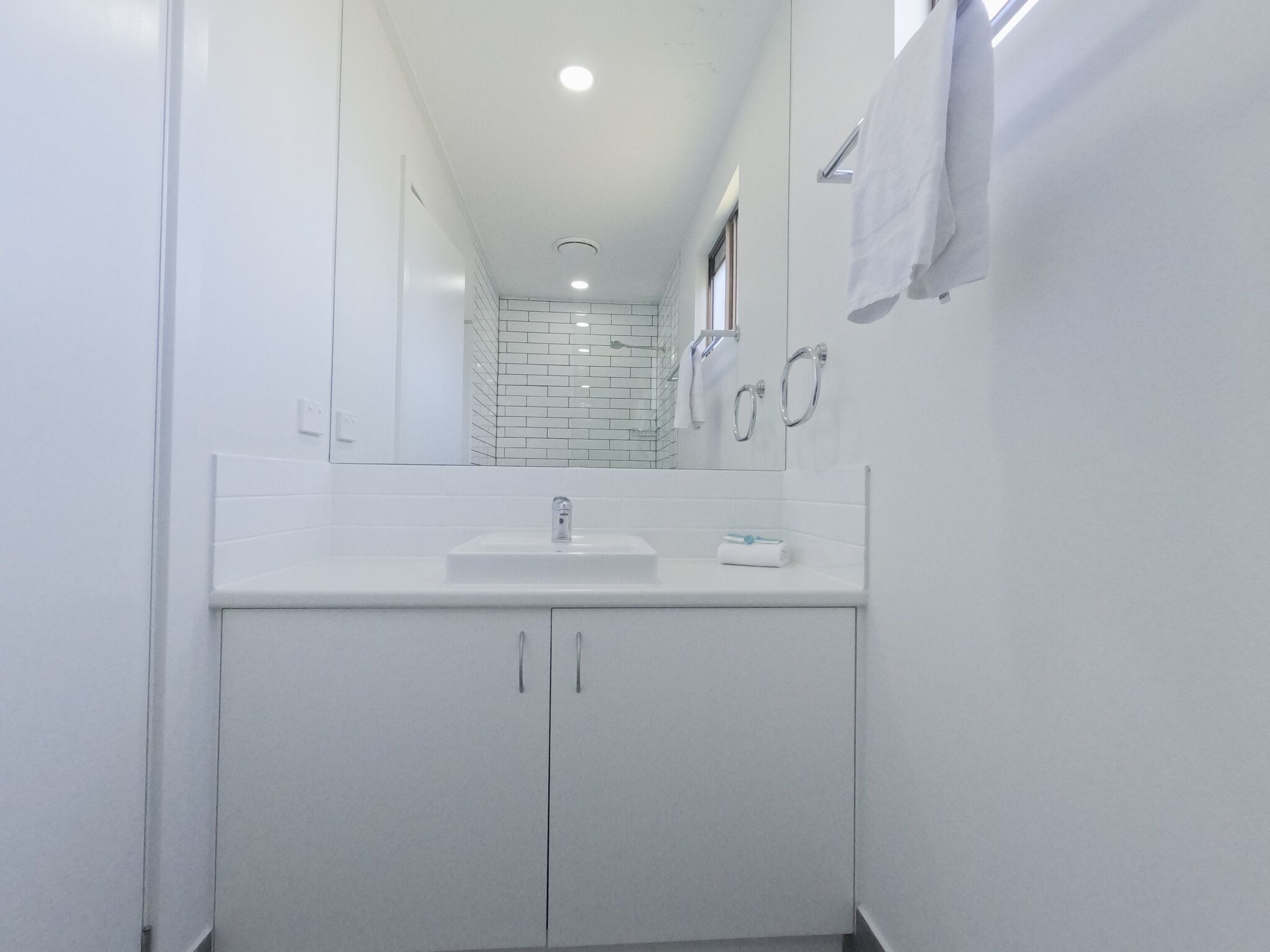 A modern bathroom with a white sink, mirror, and tiled backsplash.