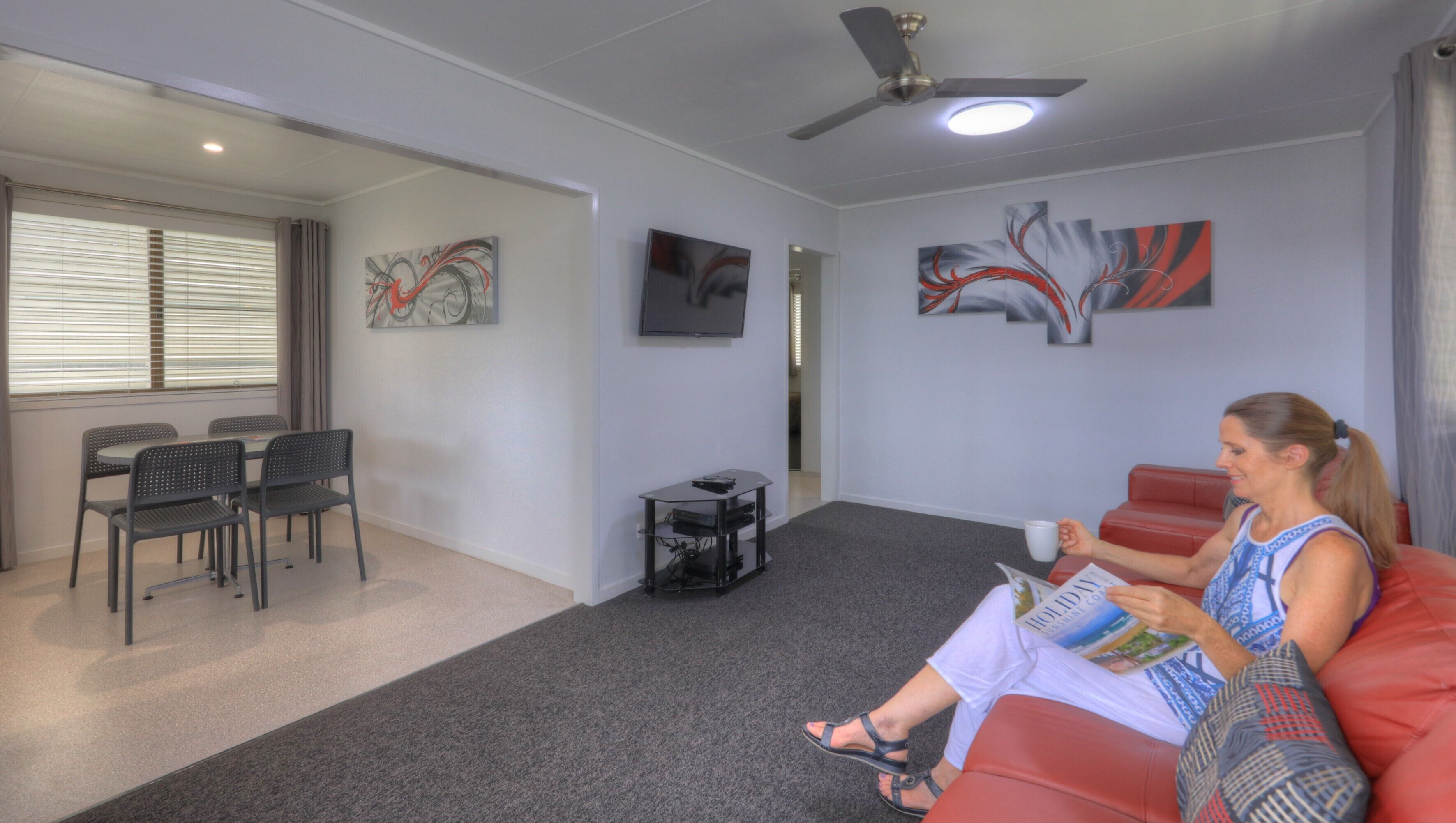A modern living room with a red sofa, a TV, and abstract wall art.