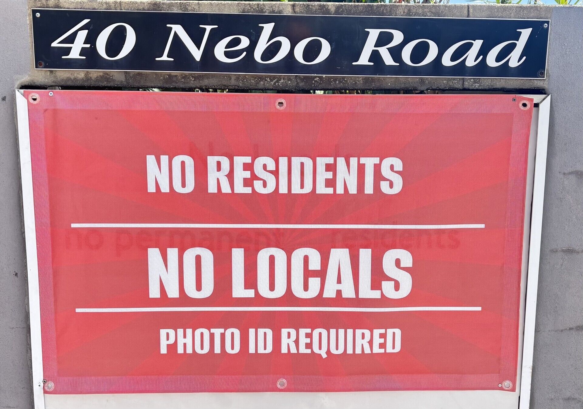 Een bord met de tekst 'GEEN INWONEN' en 'GEEN BEWONERS', met de vermelding 'IDENTITEITSKAART VERPLICHT' aan de Nebo Road 40.