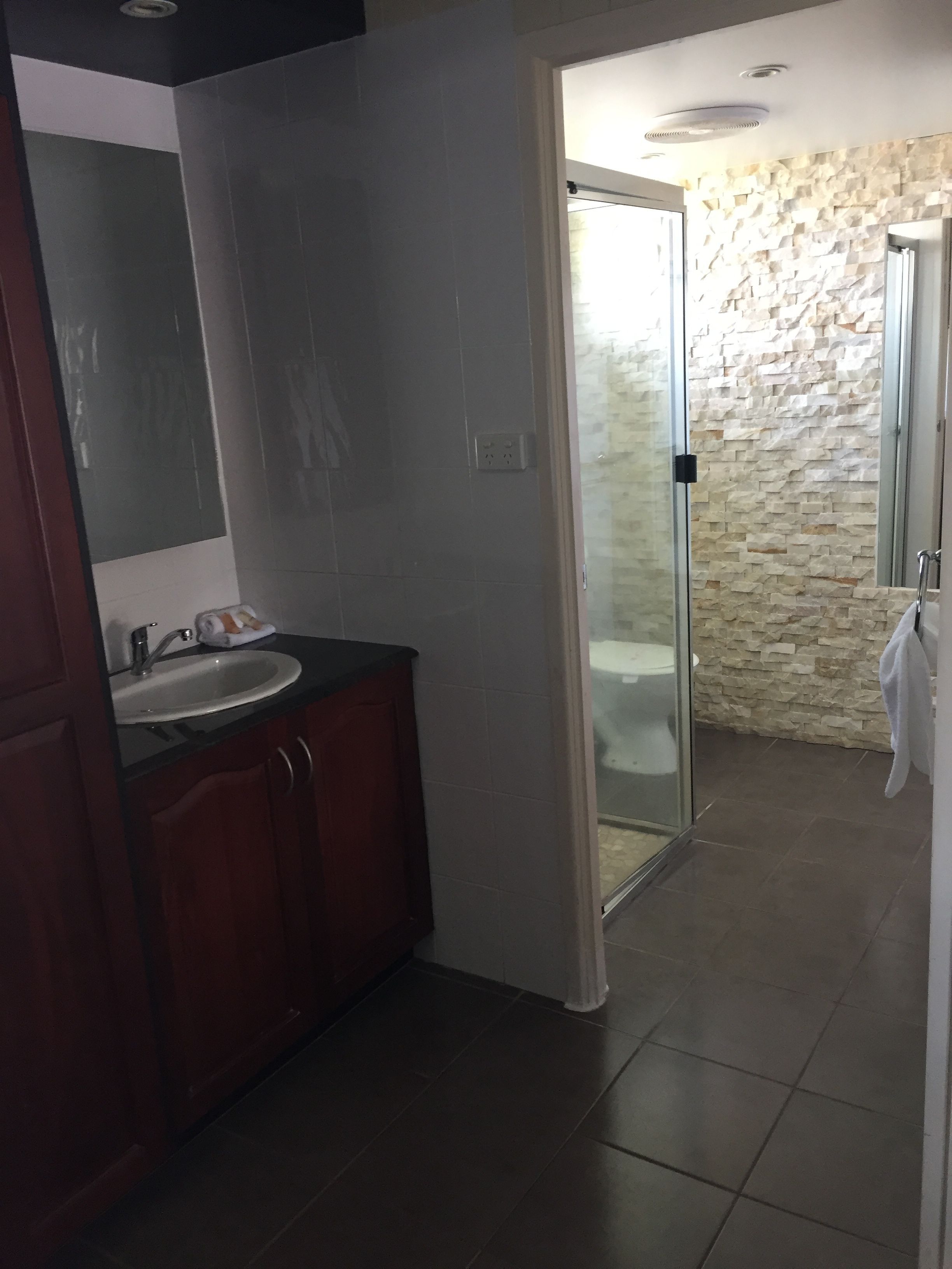 A bathroom with a glass shower door, a sink, and a mirror.