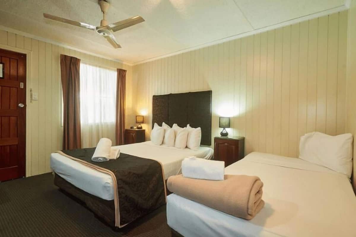 A hotel room with two beds, a ceiling fan, and two bedside tables with lamps.