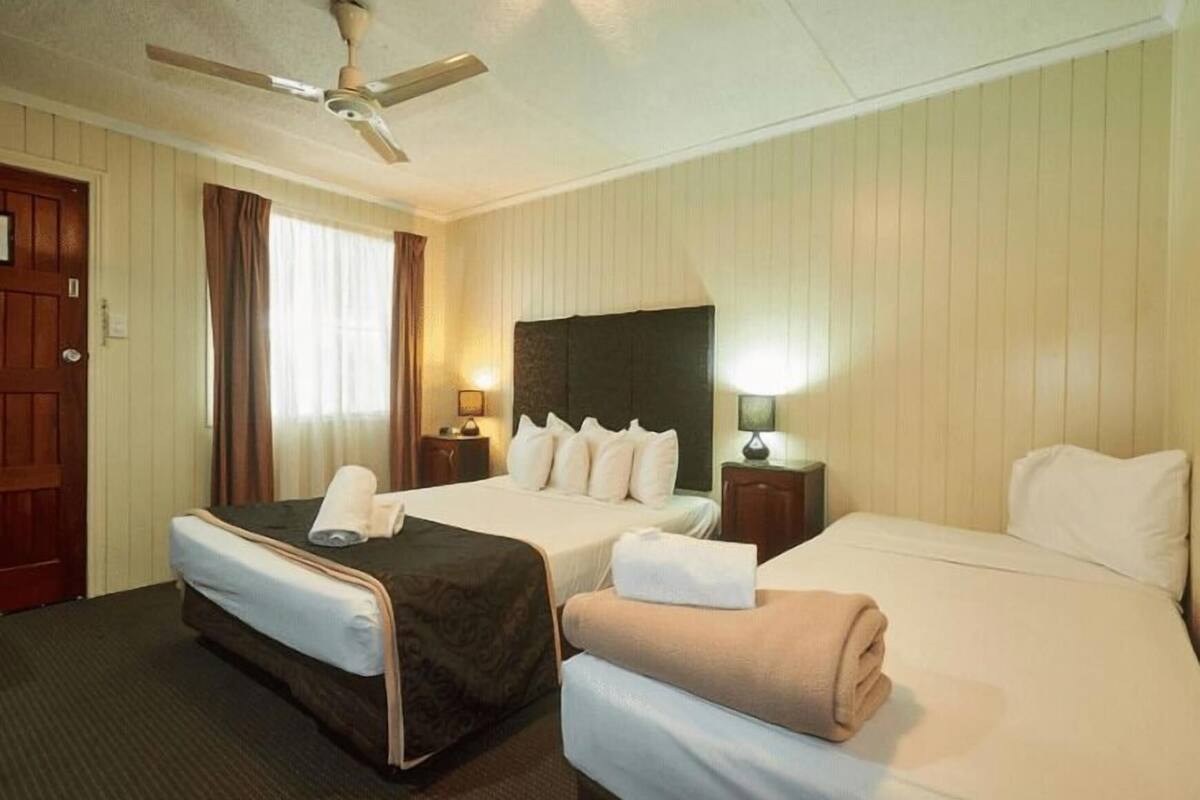 A hotel room with two beds, a ceiling fan, and two bedside tables with lamps.