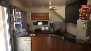 A kitchen with a stone backsplash, wooden counter, and a ceiling fan. - Country Plaza Motor Inn (West Mackay)