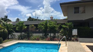 A swimming pool with a metal ladder, surrounded by a fence and various plants. - Country Plaza Motor Inn (West Mackay)