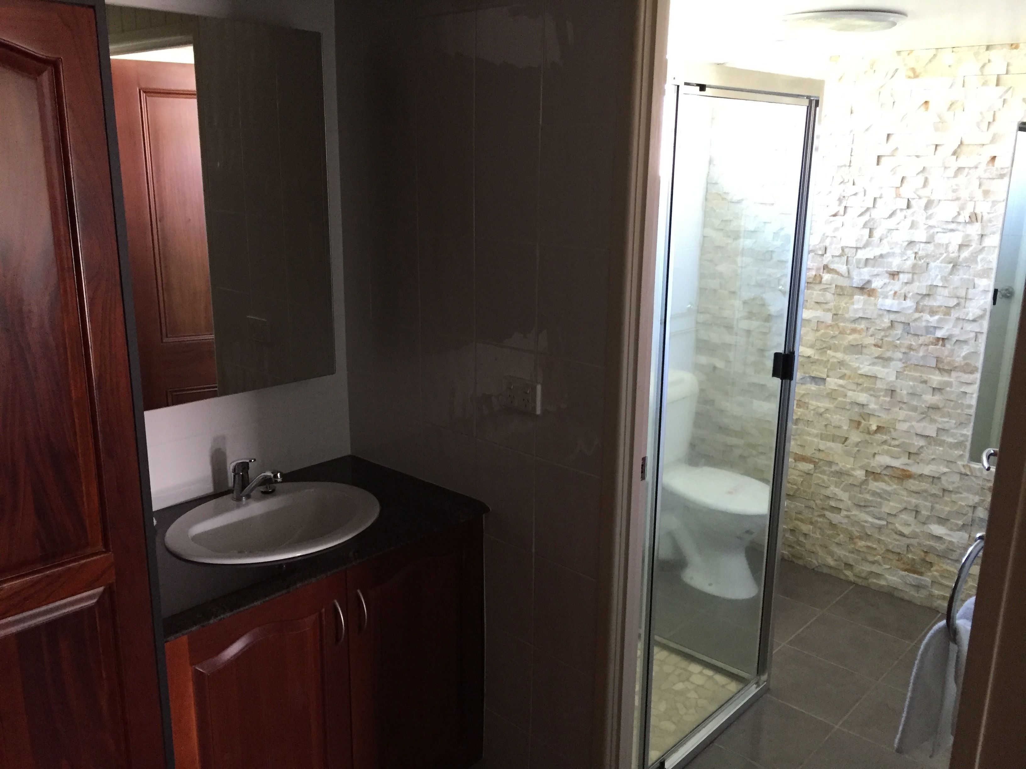 A bathroom with a wooden vanity, a mirror, a sink, and a glass shower enclosure.