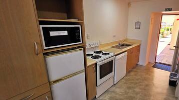 Una cocina compacta equipada con microondas, refrigerador, estufa y lavaplatos.