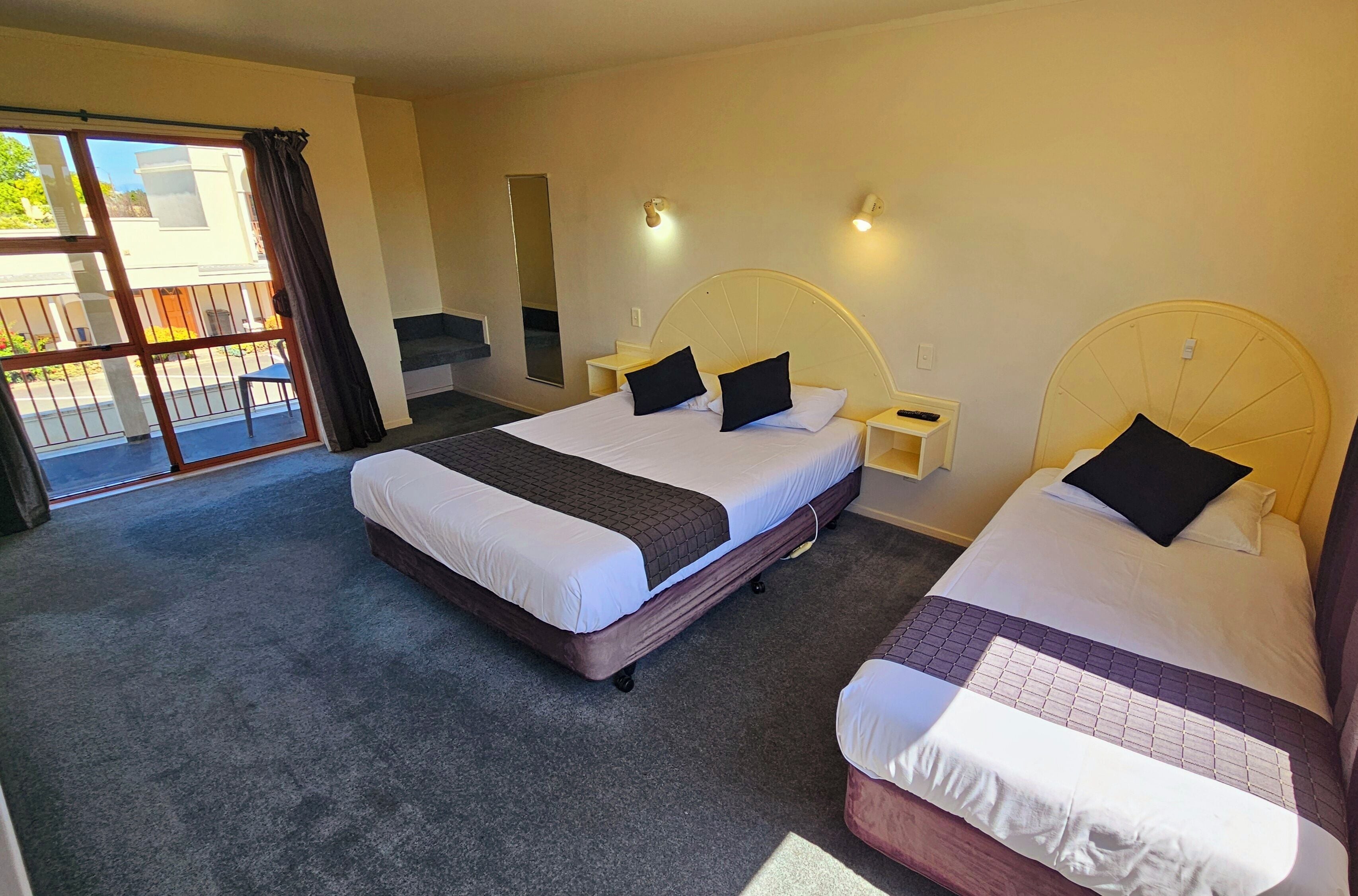 Een hotelkamer met twee bedden, een groot raam met uitzicht en een balkon met een leuning.