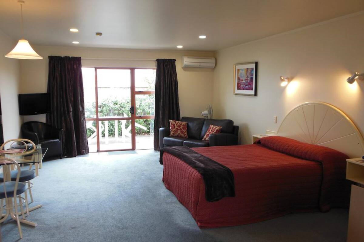 A bedroom with a bed, a sofa, a TV, and a balcony.
