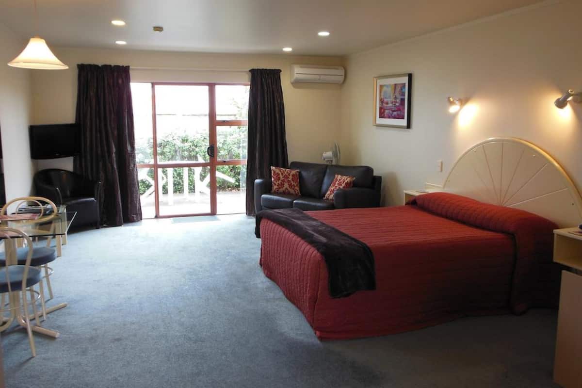 A bedroom with a bed, a sofa, a TV, and a balcony.