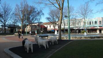 Une place publique avec une fontaine, des bancs et une statue de moutons.