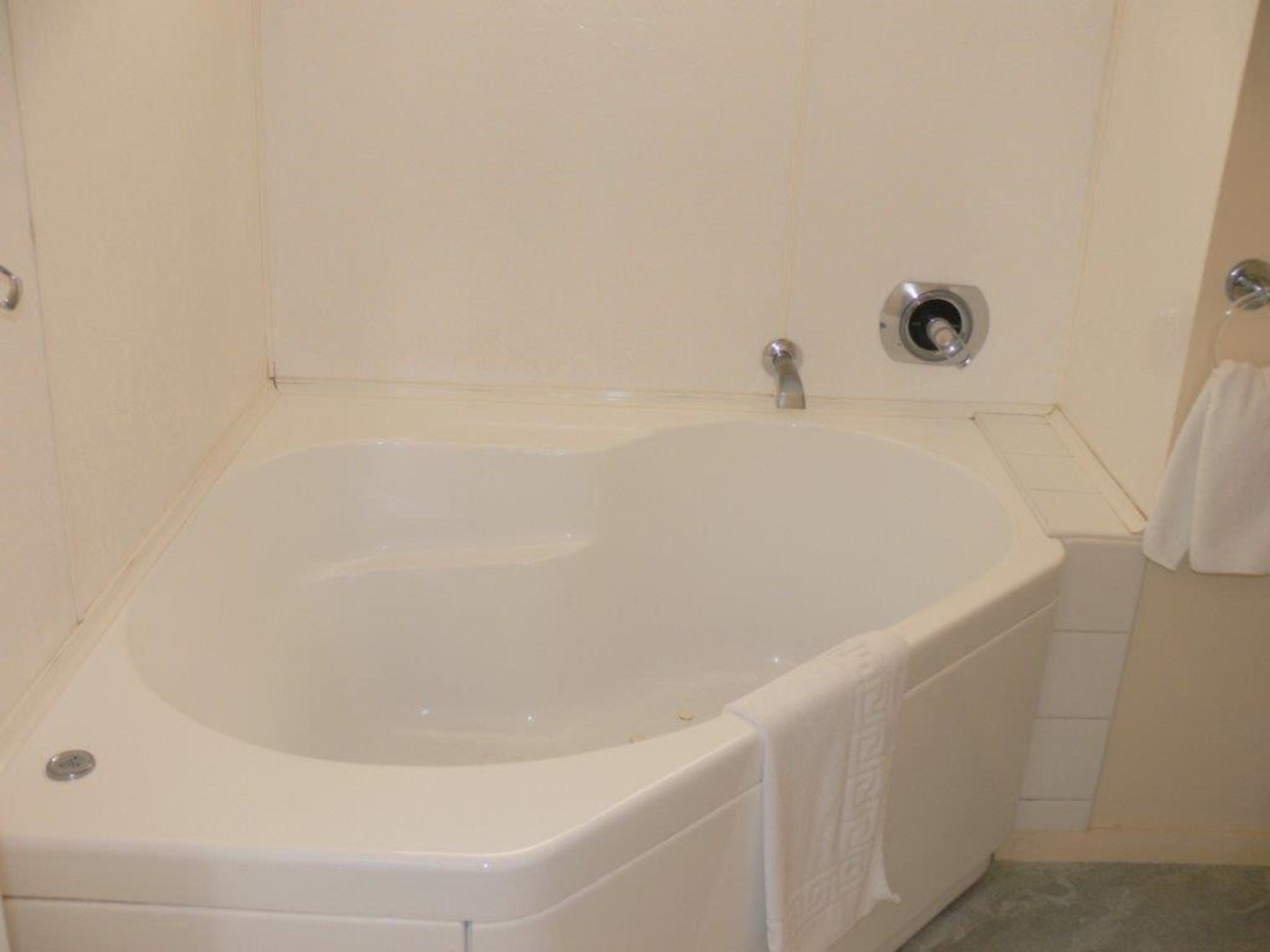 A white bathtub with a single faucet and a drain.