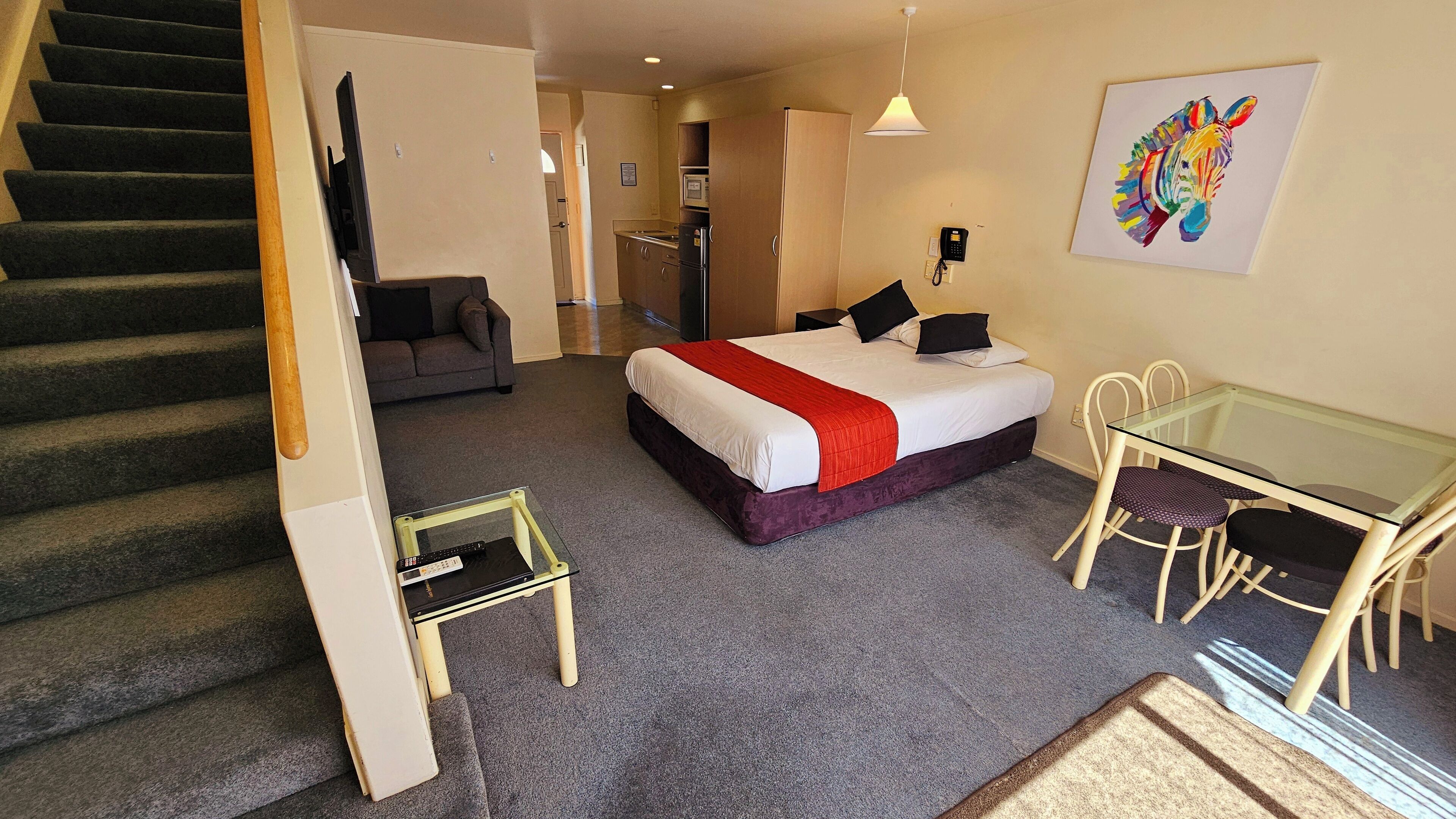 Una habitación de hotel con una cama, un escritorio, una silla, una escalera y un sofá.