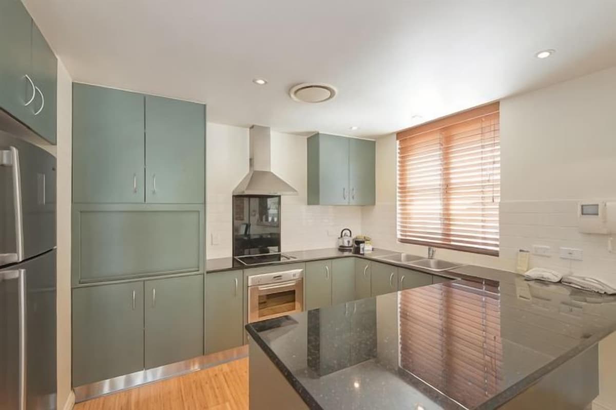 Una cocina moderna con una isla central, electrodomésticos de acero inoxidable y armarios de colores claros.