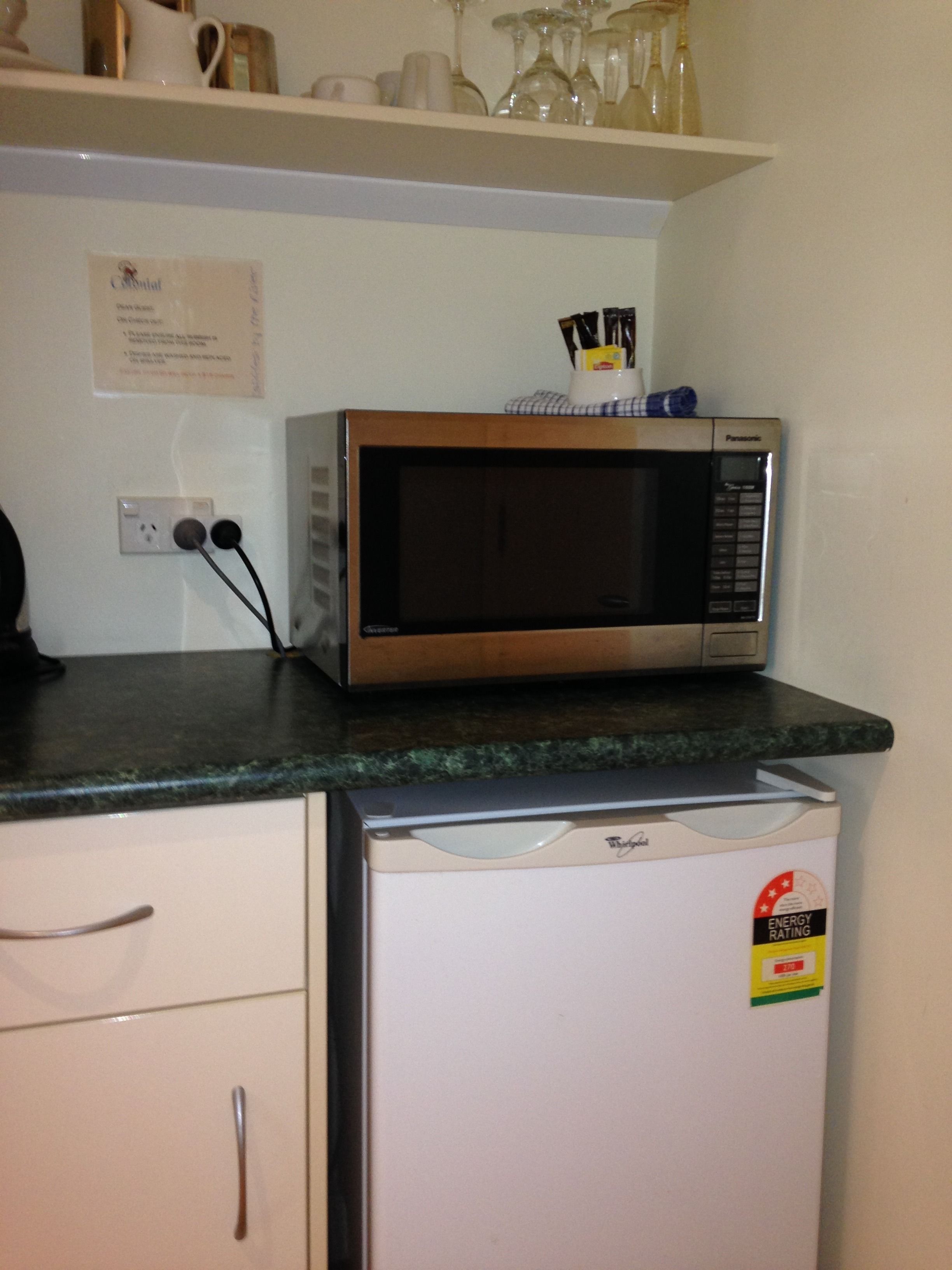 Una cocina con microondas en la encimera, lavavajillas y un cartel en la pared.