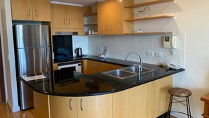 Una cocina moderna con armarios de madera, un refrigerador de acero inoxidable, un microondas, una cafetera y un lavabo.
