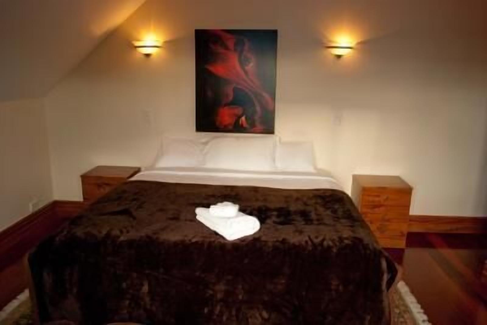 A bedroom with a large bed, two bedside tables, and a painting on the wall.