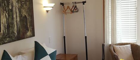 Hotelkamer met een groot bed, een staande lamp, een schilderij, een kruk, een stoel en een raam met gordijnen.