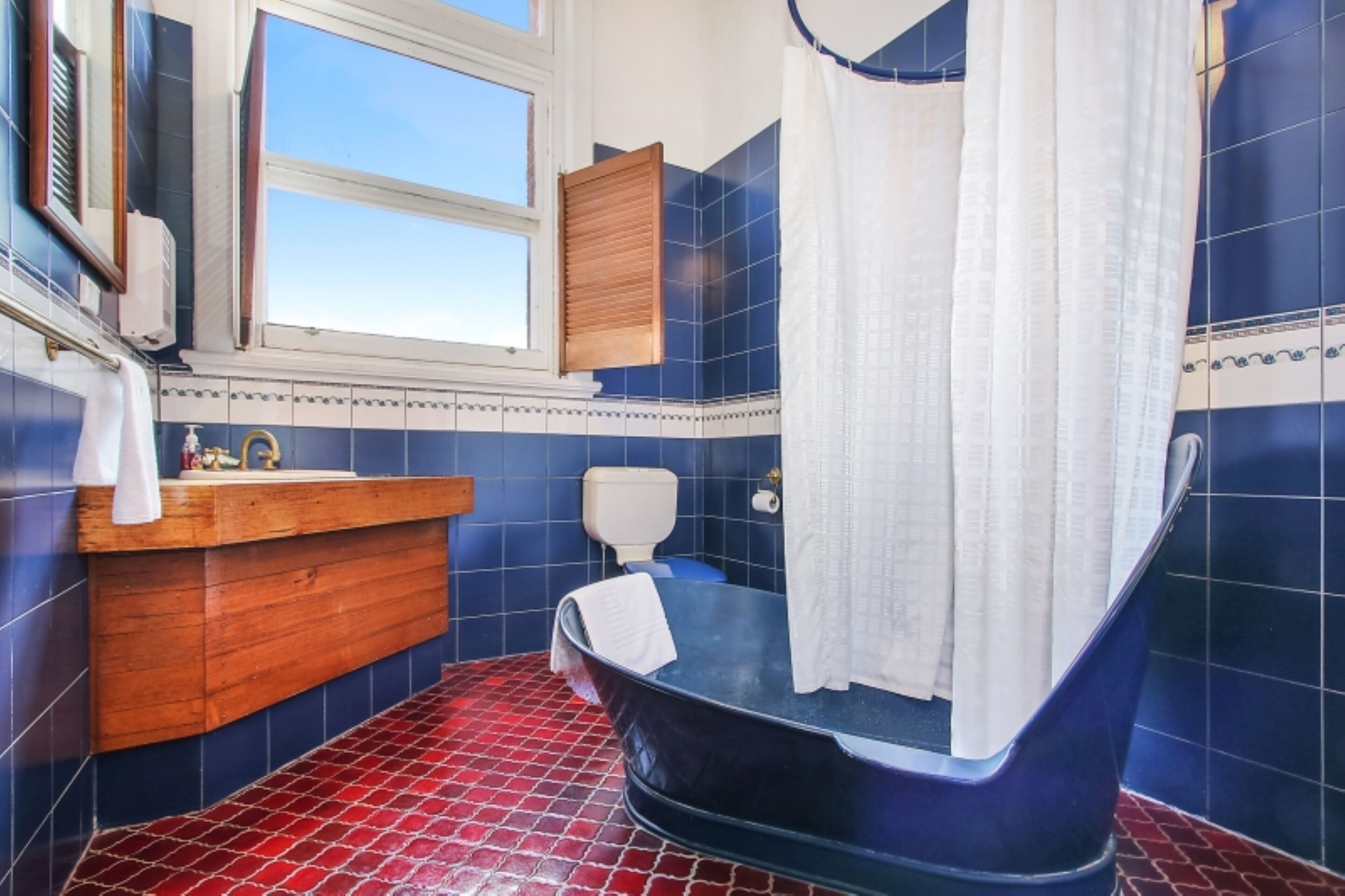 Un baño con bañera, tocador de madera, inodoro y ventana.