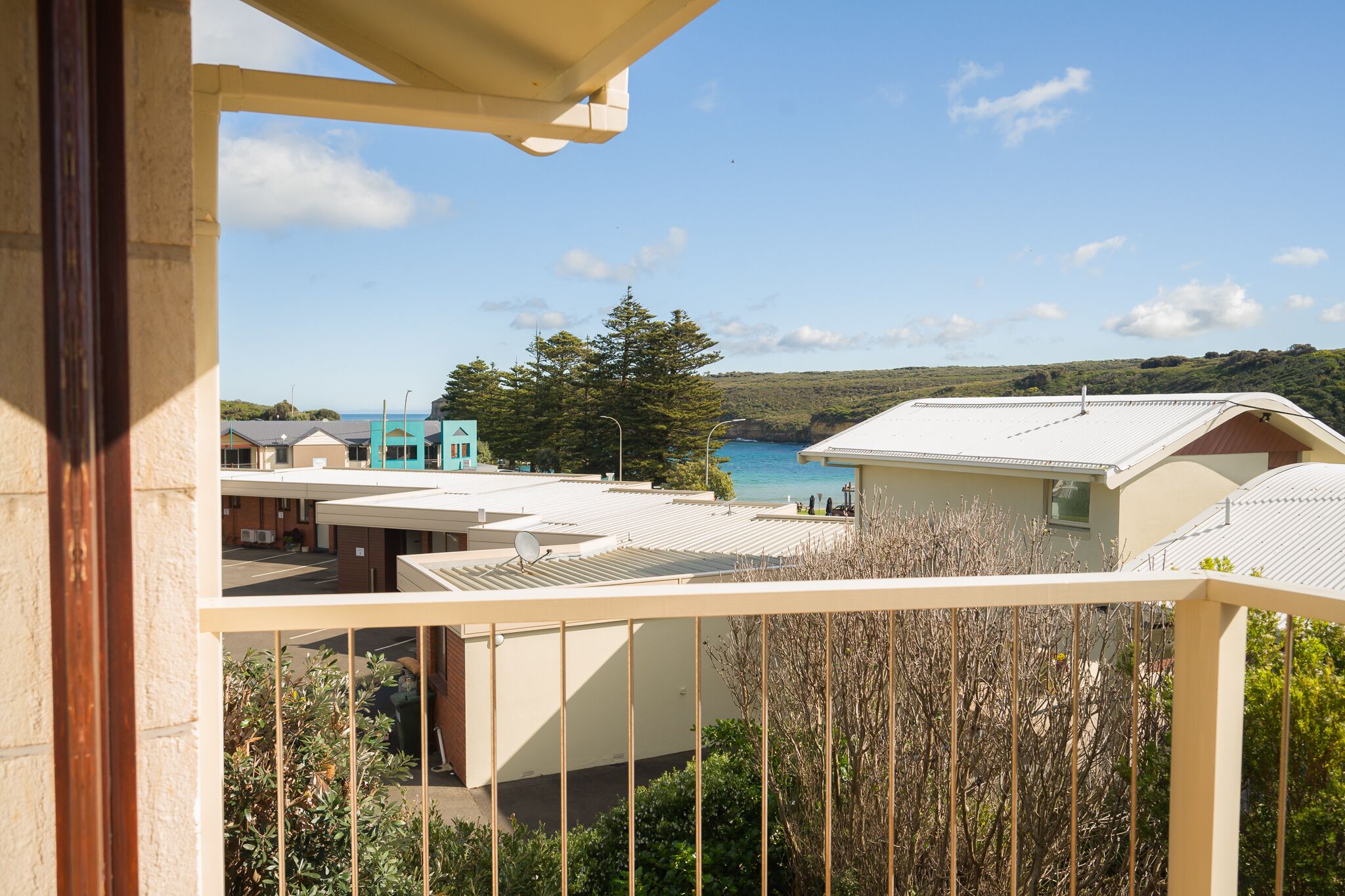 A balcony with a view of a coastal area, including buildings and a body of water.
