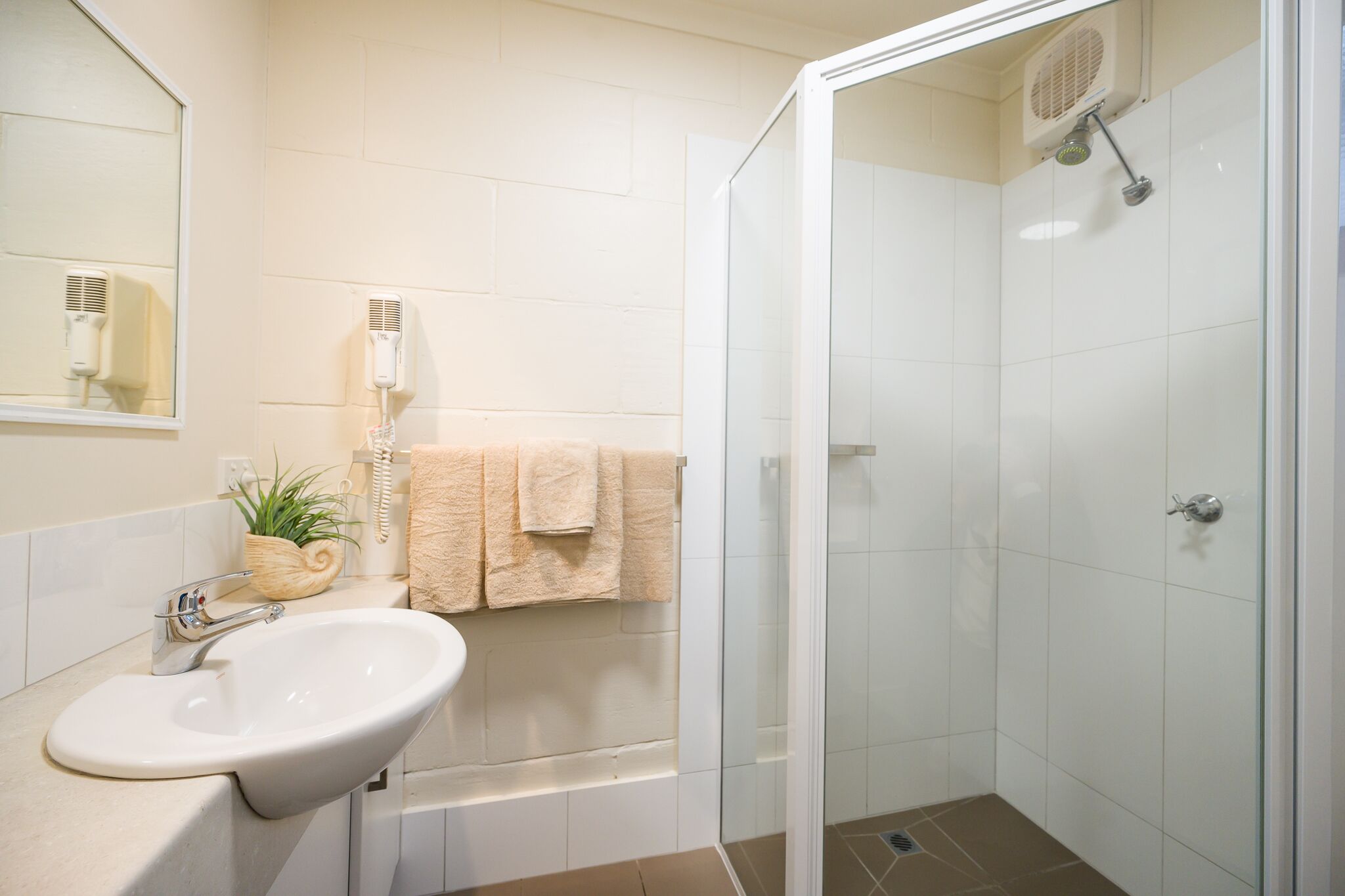 A bathroom with a sink, mirror, towel rack, and shower.