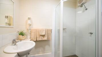 A bathroom with a sink, mirror, towel rack, and shower.