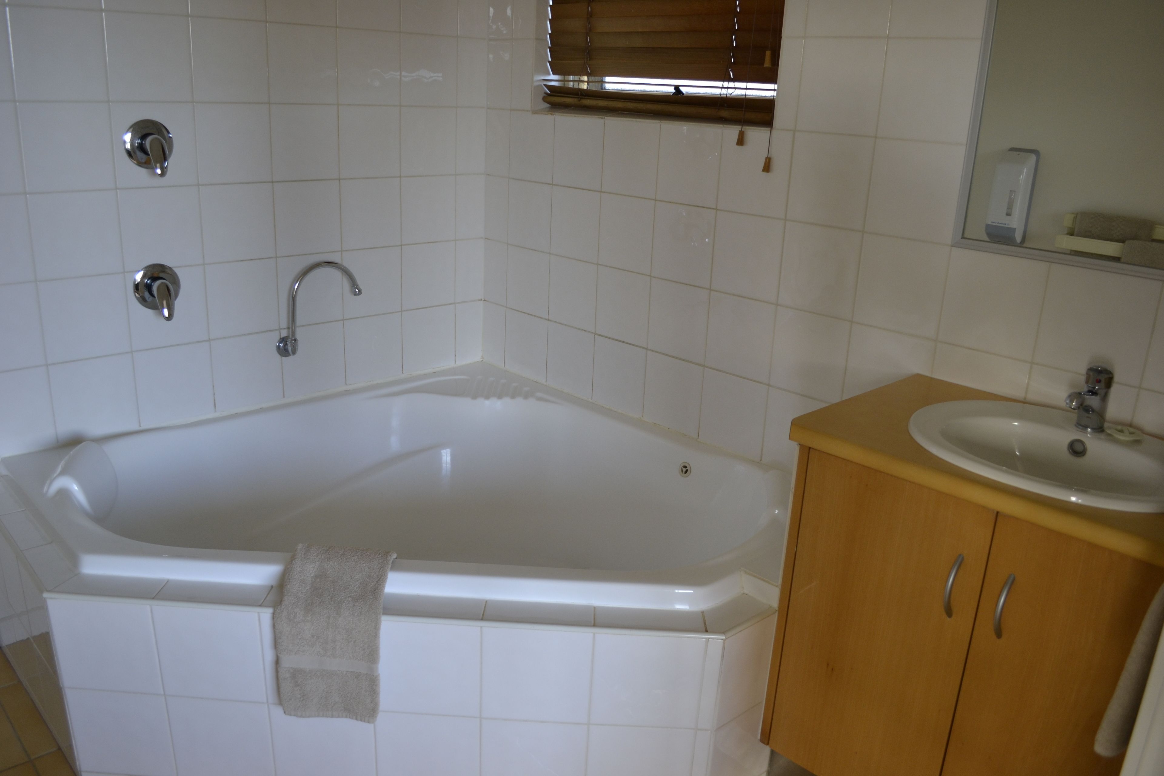 Een badkamer met een badkuip, een wastafel en houten kastjes.