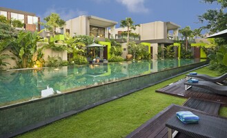 Un hôtel moderne doté d’une piscine, de pelouses verdoyantes et d’espaces de détente avec des chaises longues.