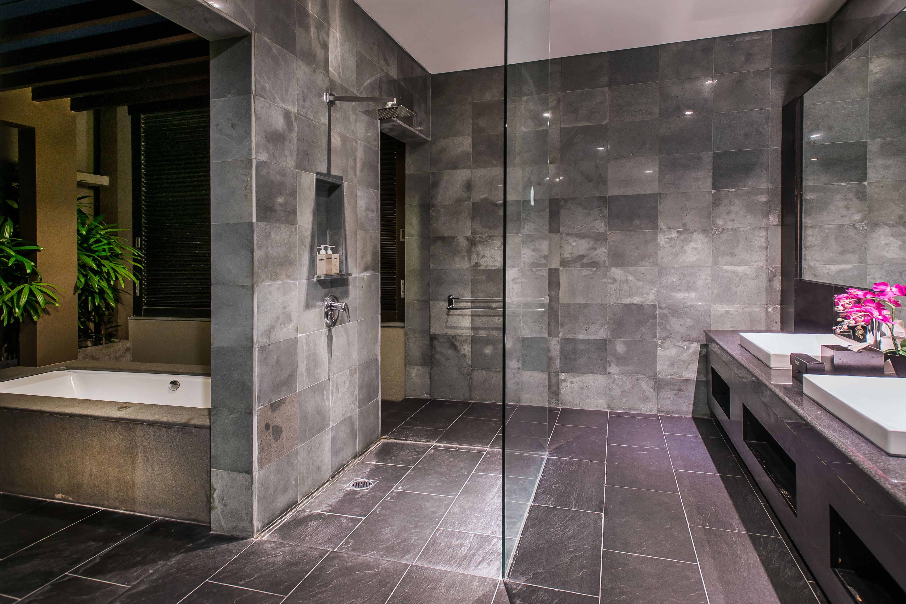 A modern bathroom with a glass-enclosed shower, a bathtub, and a vanity with a mirror.