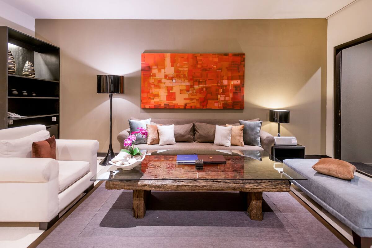 A modern living room with a sofa, a coffee table, and a large abstract painting on the wall.