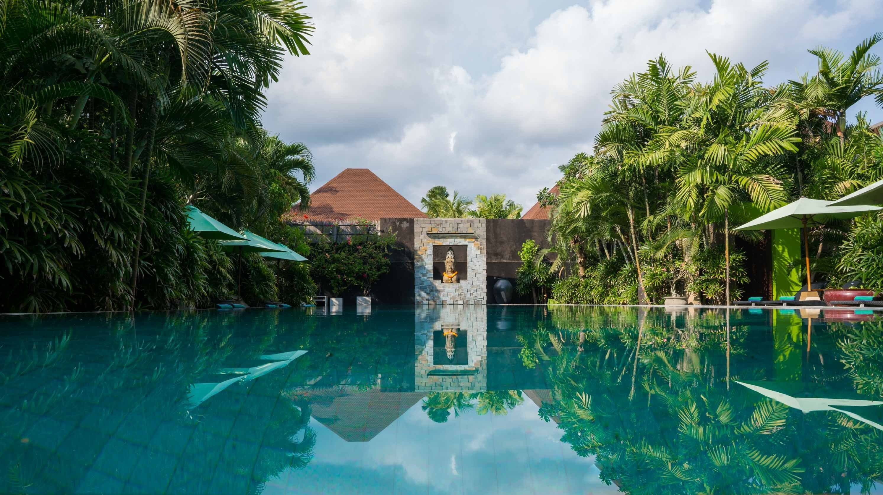 On aperçoit clairement une piscine, avec un chemin de pierre qui mène à un bâtiment doté d’un toit en tuiles.