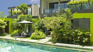 A modern pool area with lounge chairs, a small table, and a palm tree.