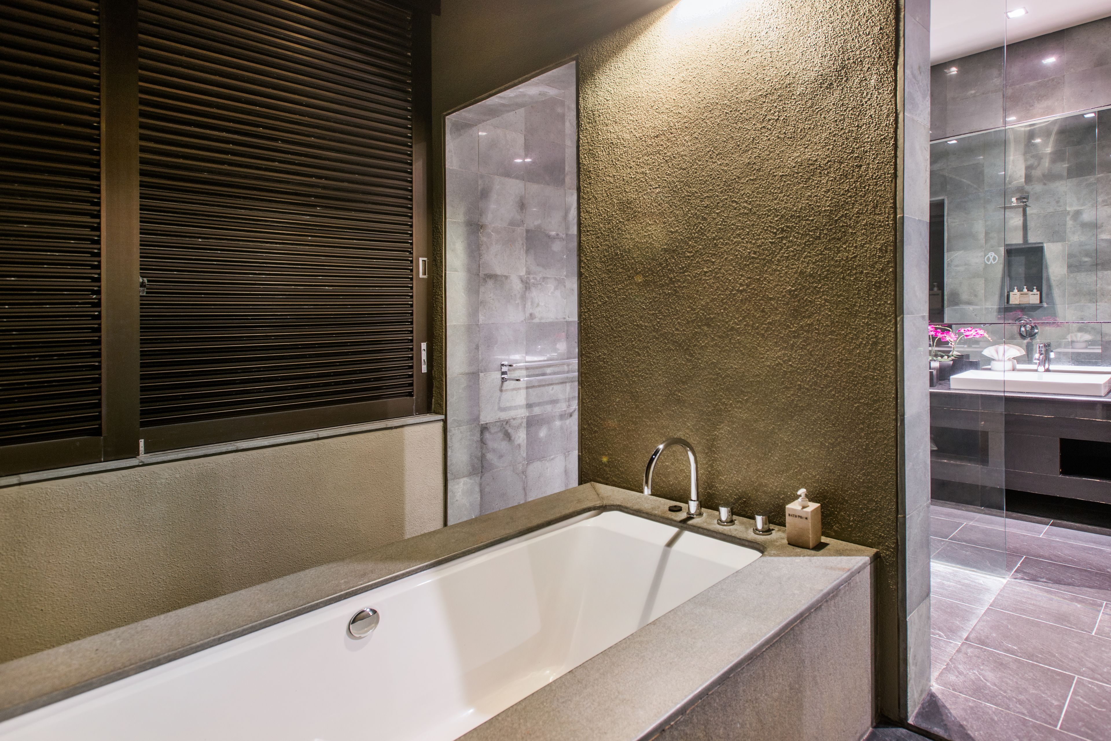Un baño moderno con una bañera grande, cabina de ducha con mampara de vidrio y vistas a la ciudad a través de la pared de cristal.