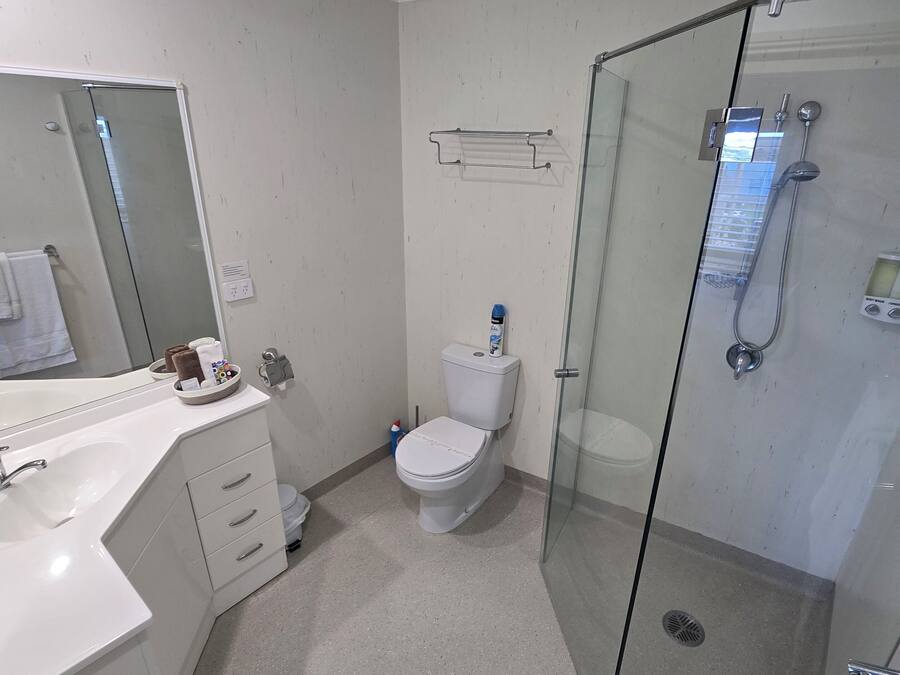 A bathroom with a toilet, sink, shower, and a glass-enclosed shower stall.