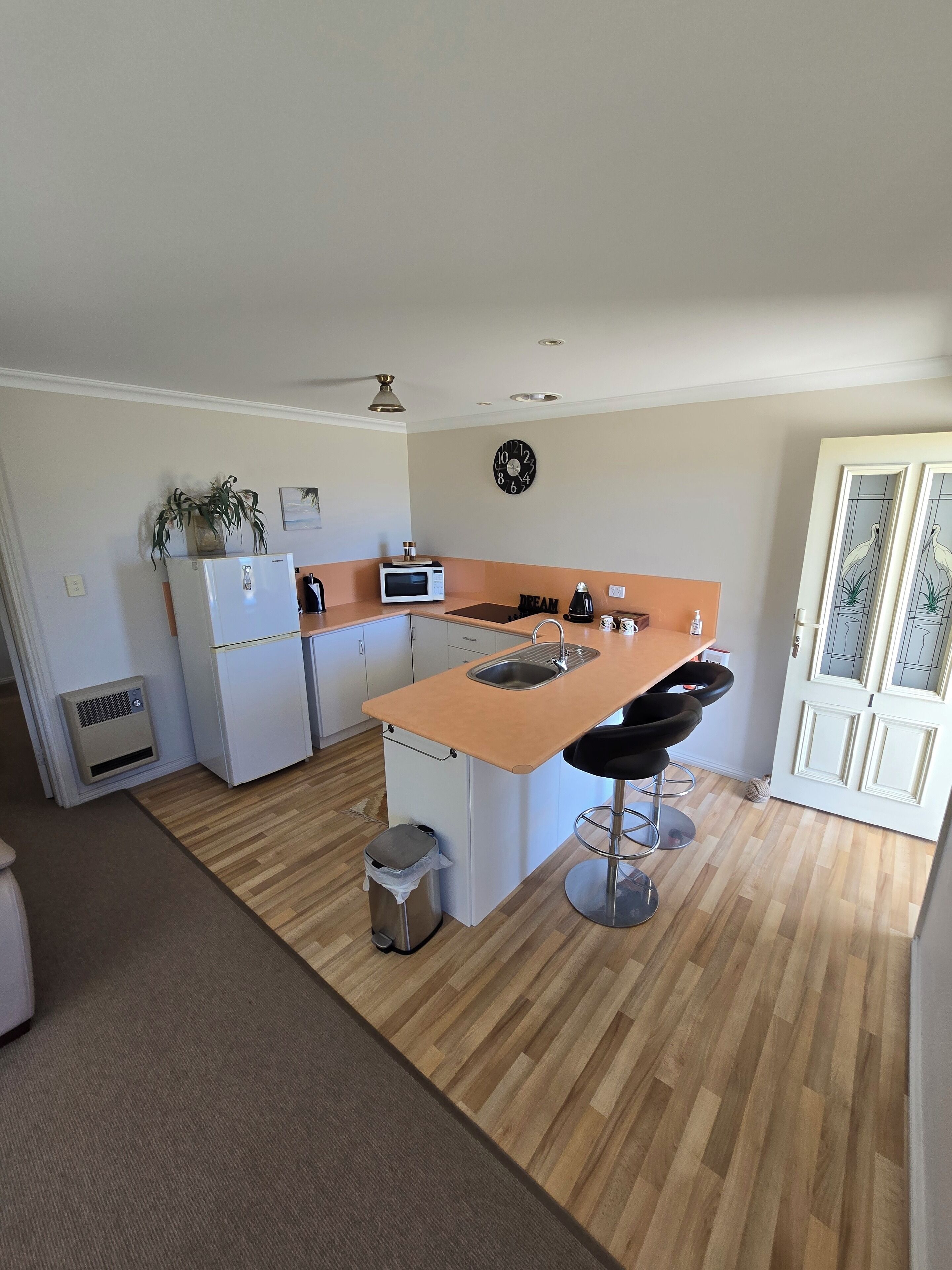 A compact kitchen with a central island, white cabinetry, a microwave, a refrigerator, and a sink.