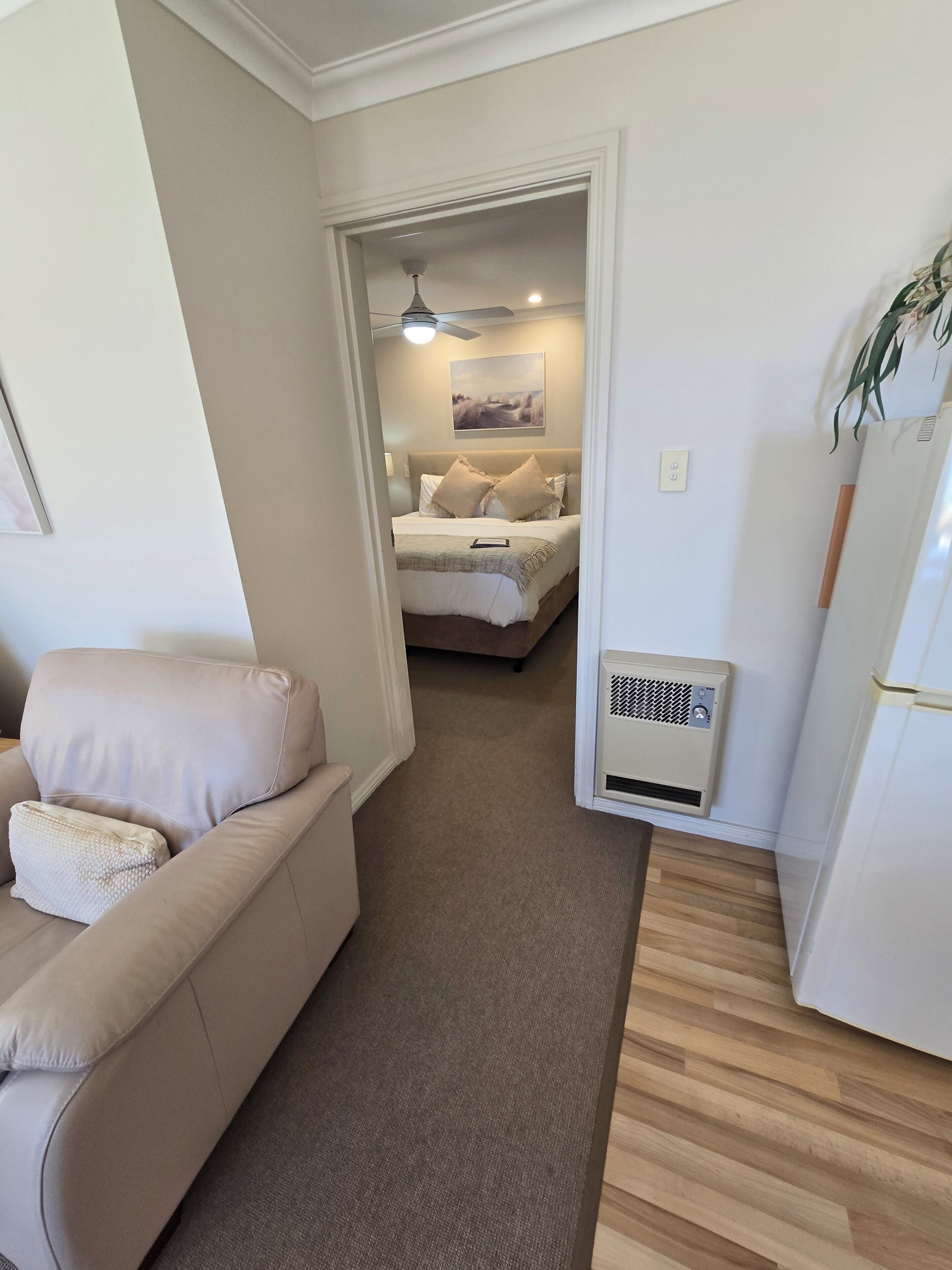 Une chambre à coucher moderne et bien éclairée, avec un lit, une table de chevet et un ventilateur de plafond.