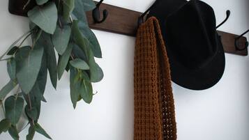 A wall-mounted coat rack with a black hat and a brown scarf.