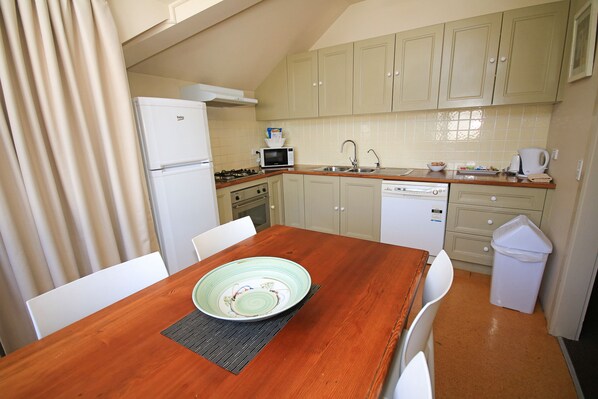 A compact kitchen with basic appliances, a dining table, and chairs.