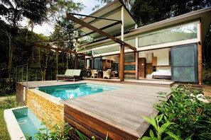 Ein modernes Haus mit Swimmingpool, Holzterrasse und großen Glasfenstern.