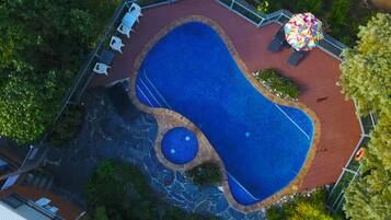 Relax by the pool surrounded by lush greenery and lounge chairs.