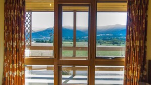 Una habitación con un amplio ventanal que ofrece vistas de un paisaje montañoso.