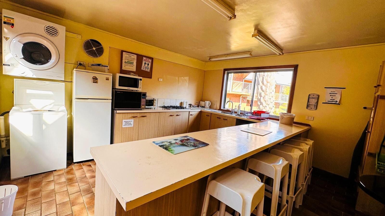 A compact kitchen with a central island, a washing machine, a microwave, and a refrigerator.