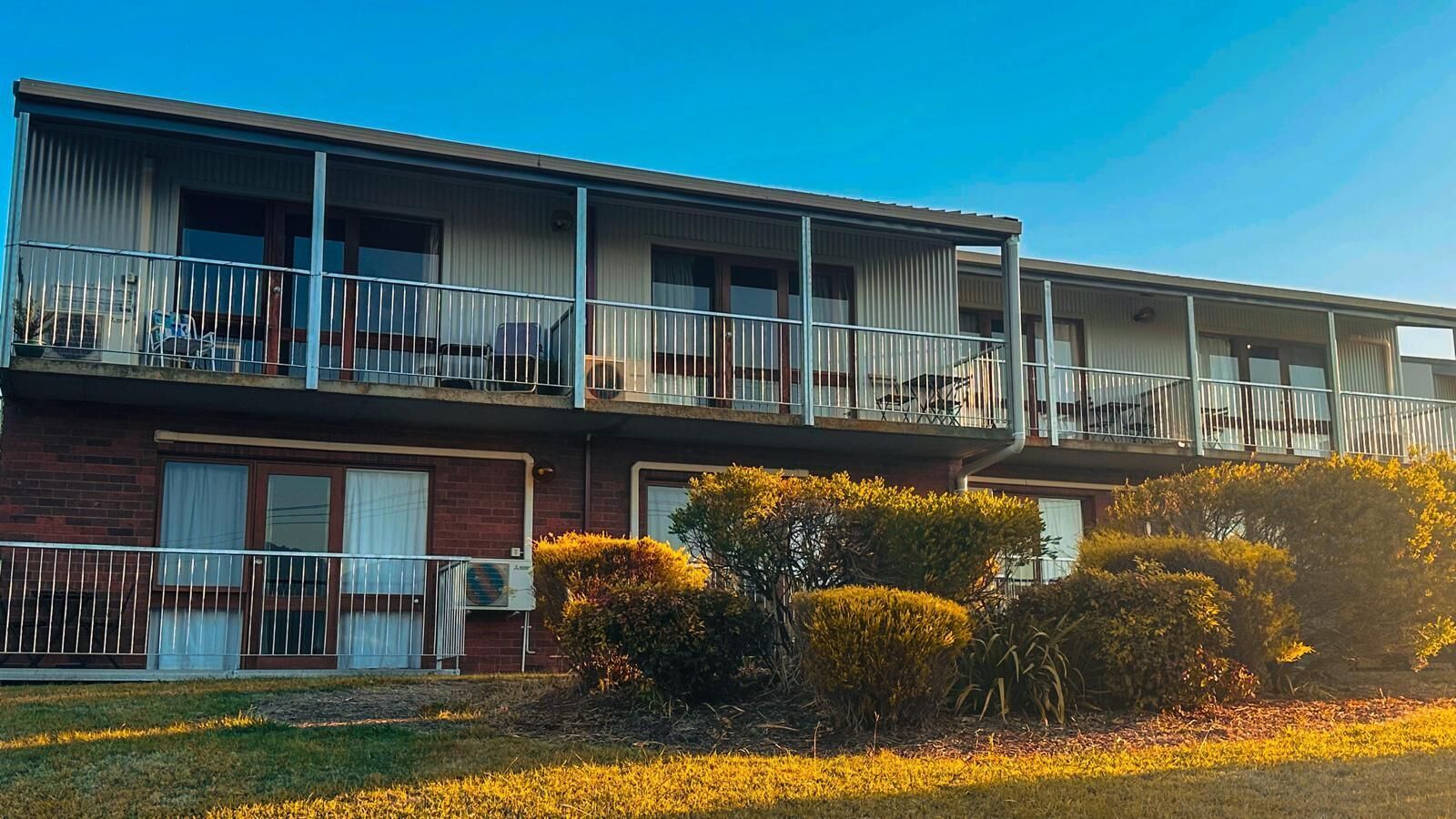 A two-story motel with a flat roof, a brick facade, and a balcony on the upper floor.