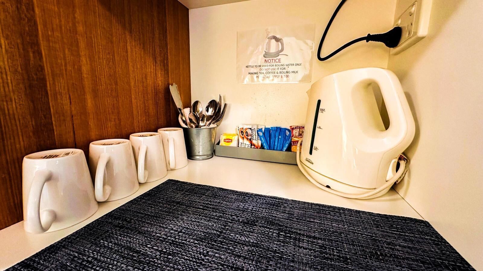 Una zona de cocina con hervidor, tazas y cafetera.