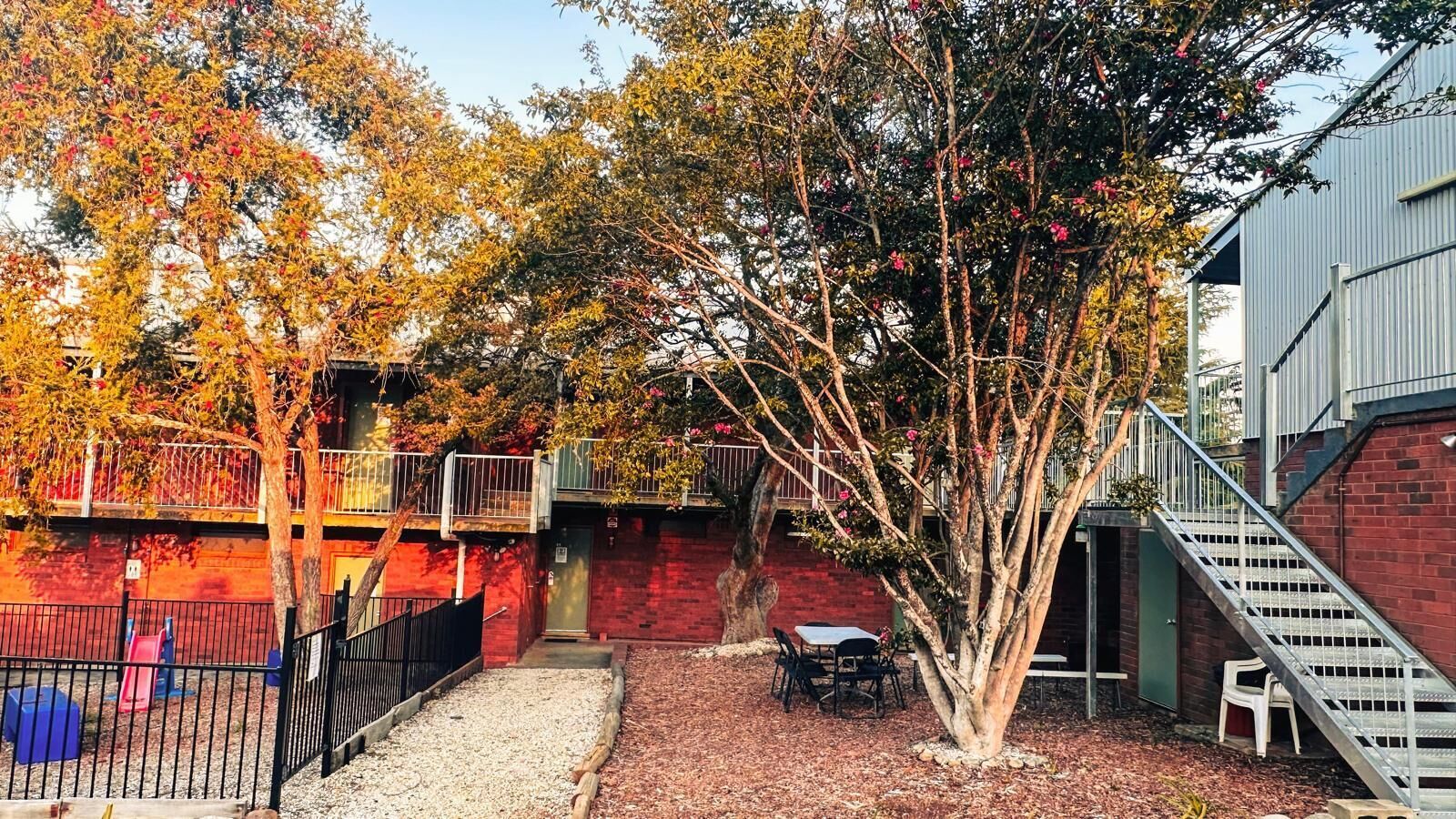 A courtyard with a tree, a small table, and a staircase.