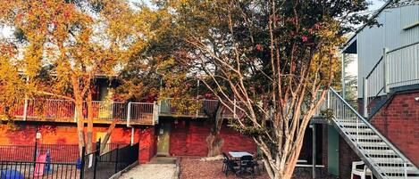 A courtyard with a tree, a small table, and a staircase.