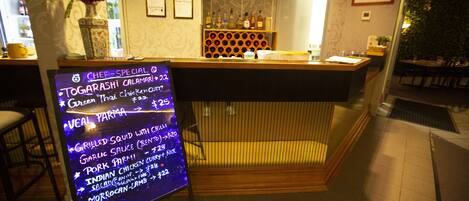 A restaurant interior with a menu board, wooden counter, and a wall with framed certificates.
