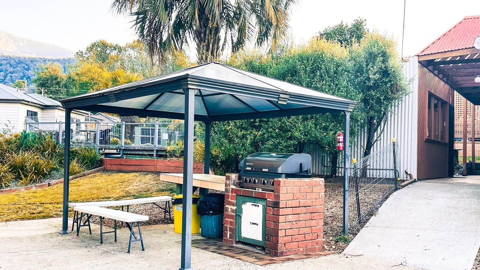 An outdoor barbecue area with a brick grill, a covered seating area, and a table.