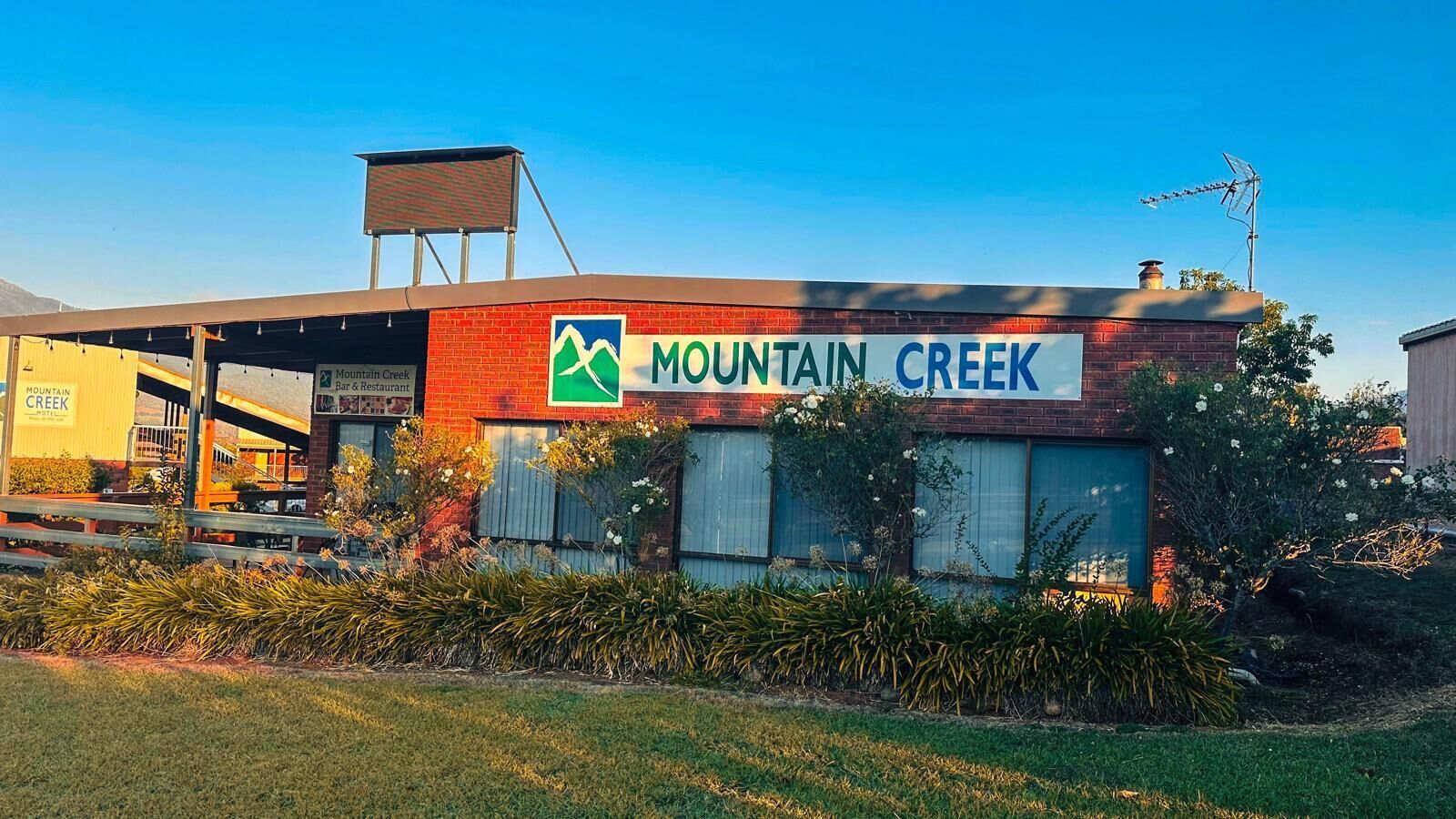 A building with a sign reading "Mountain Creek Bar & Restaurant" and a logo with a mountain and creek.