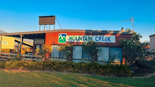 Un edificio con un letrero que dice "Mountain Creek Bar & Restaurant" y un logotipo con una montaña y un arroyo.